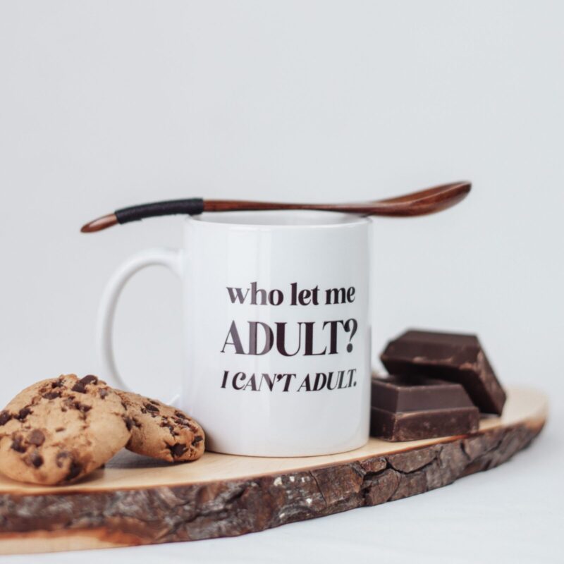 Tazza bianca con su scritto "who let me ADULT? I CAN'T ADULT."